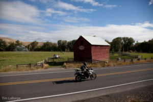 2013-July-August-Oregon-Travel-Explore-Eastern-Oregon-Tim-Labarge-Riding-by-Barn-Motorcycle