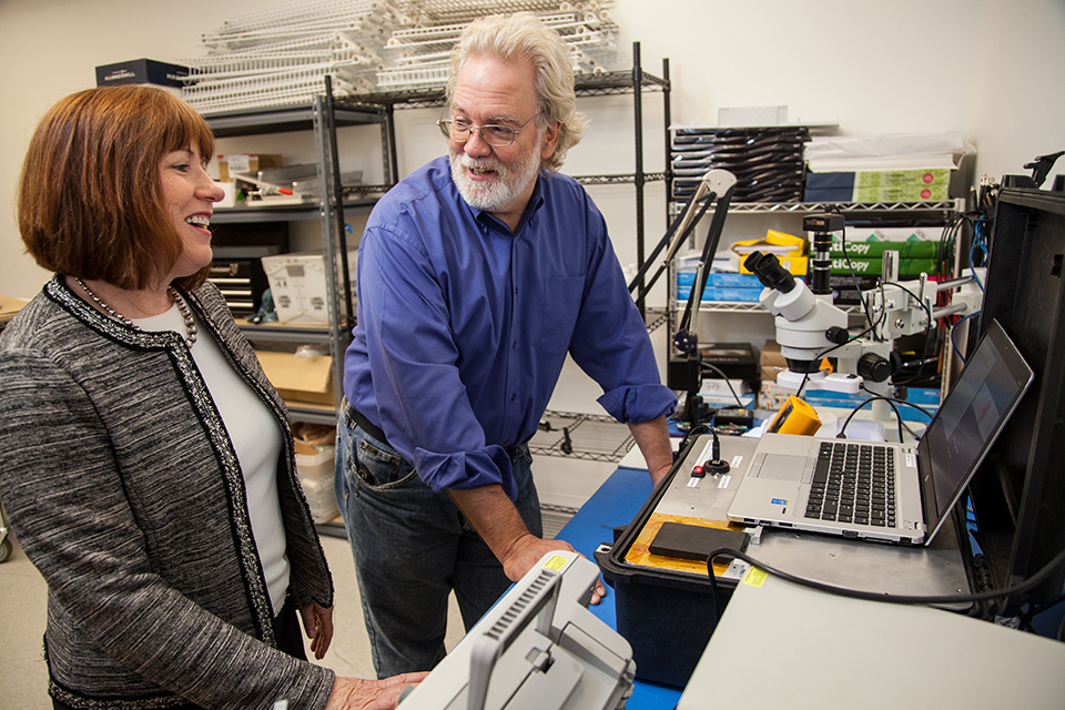 Patti White, CEO of Hemex Health, speaks with Martin Rockwell, electrical engineering manager at Andrew Cooper, about a prototype of the diagnostic equipment designed to test for sickle cell disease and malaria in a quick and inexpensive way. Photo © Tim LaBarge 2016