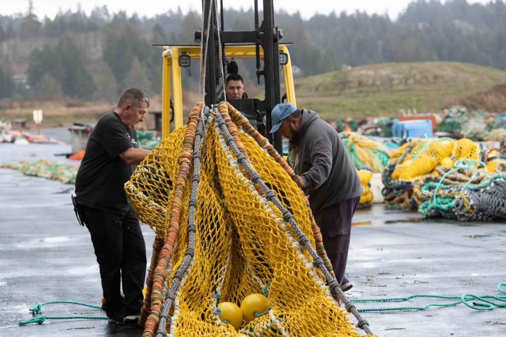 From left: Shawn Lafontaine, Hugo Hernandez, and Salvador Perez use a forklift to bundle an excluder at Foulweather Trawl on Nov. 25 in Newport, Oregon.