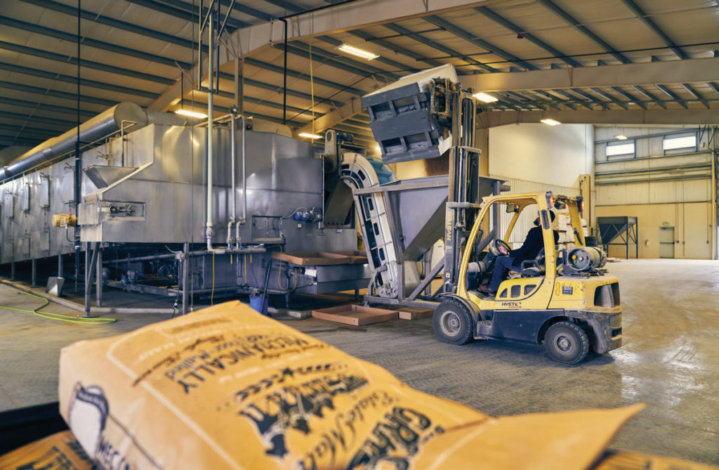Seth Klann loads fresh barley into the malter inside Mecca Grade’s malting facility adjacent to the tasting room.
