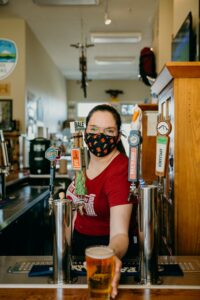 Masked woman bartending