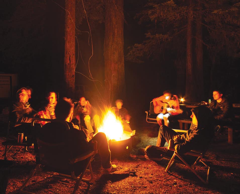 Participants sit around a campfire during a multi-day Cog Wild mountain biking and camping trip in the Mckenzie River area.
