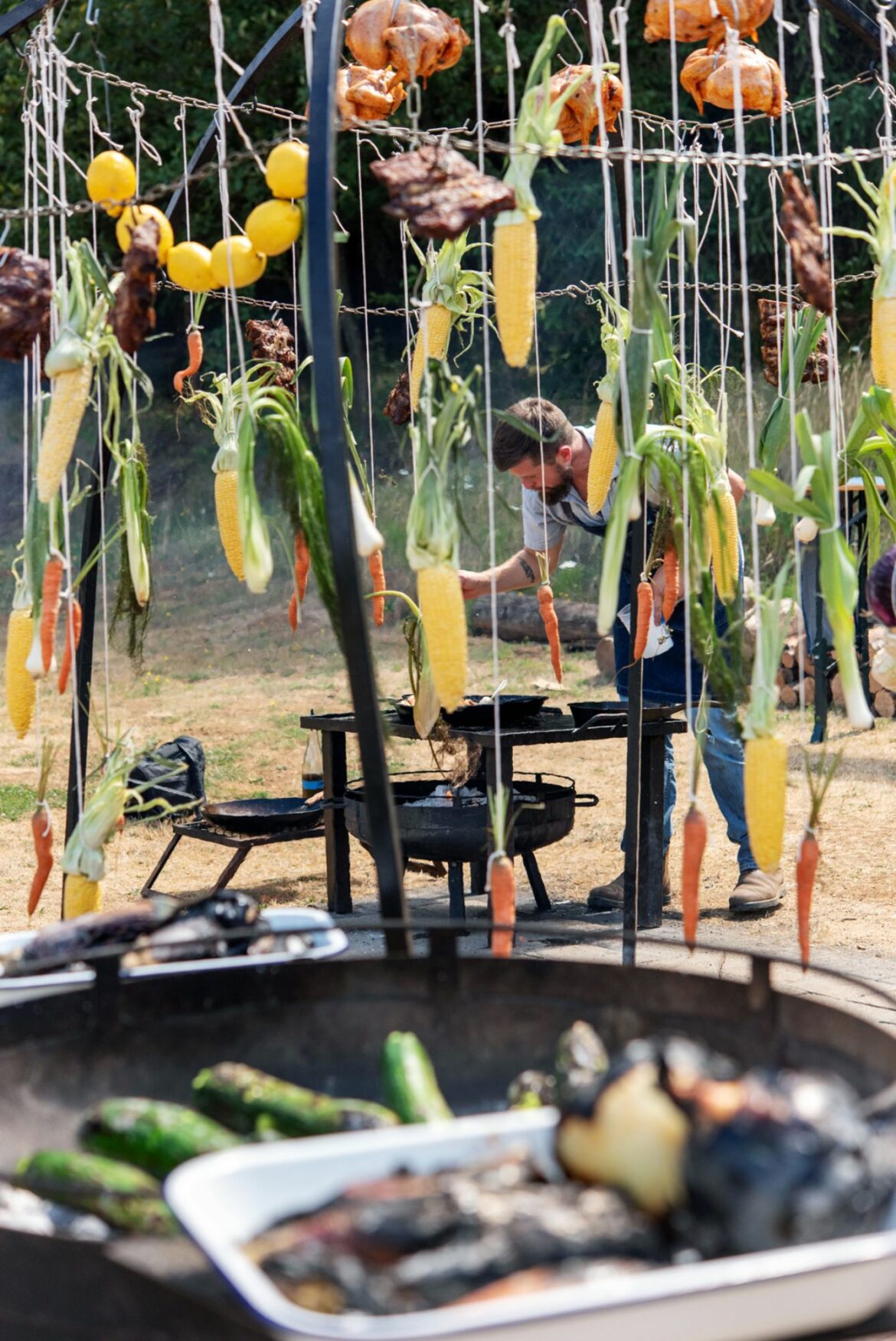 Meat and vegetables hang from a fire dome during Tournant’s recent Oregon Asado event near Dundee.