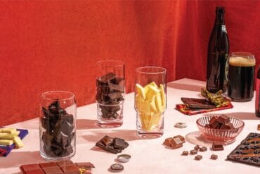 Enjoy a pairing of fine chocolates and craft beers, showcasing a variety of dark, milk, and white chocolates alongside rich, frothy beers for a delightful tasting experience.