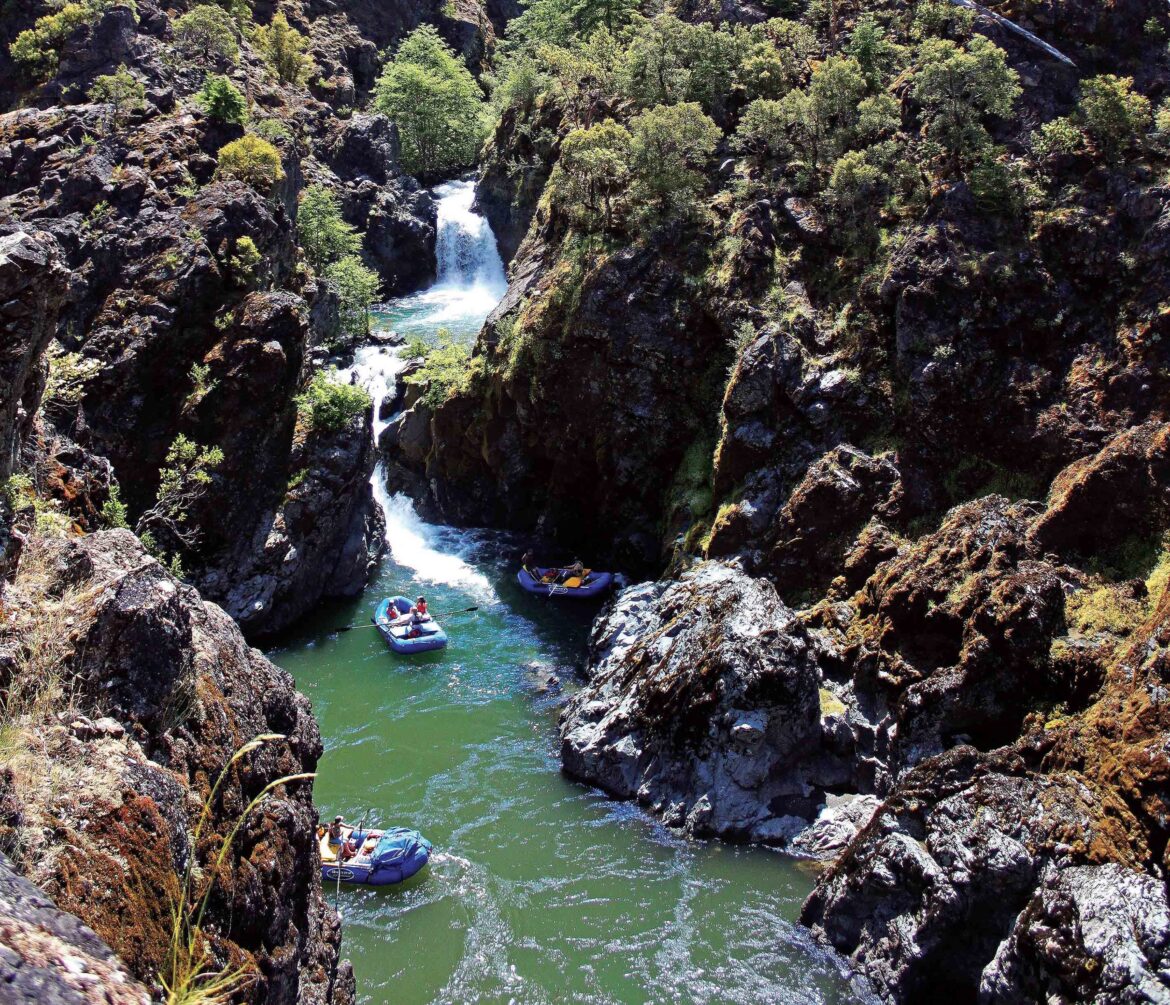 Rafters paddle by Stair Creek Falls during a Momentum River Expeditions trip on the Rogue River.