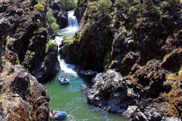 Rafters paddle by Stair Creek Falls during a Momentum River Expeditions trip on the Rogue River.