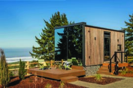 Modern tiny home with ocean view and outdoor deck in Oregon, surrounded by lush trees