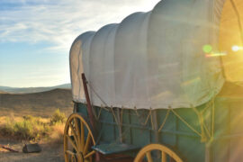 Covered wagon in a rural Oregon landscape during sunset, showcasing Oregon history and pioneer heritage, ideal for Oregon travel, culture, and scenic exploration.