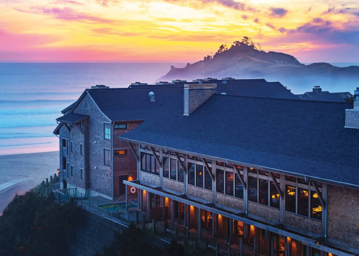 Beautiful view of Headlands Coastal Lodge & Spa overlooking the ocean at sunset, with a scenic island in the background, showcasing Oregon’s stunning coastal landscape.