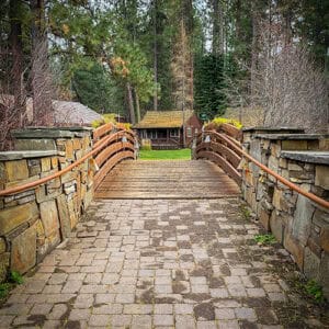 Bridge leading to Lake Creek Lodge surrounded by lush forest.